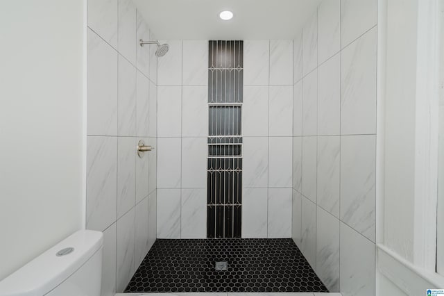 full bathroom featuring a tile shower and toilet