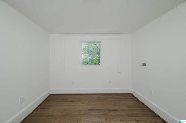 spare room with crown molding and dark wood-type flooring