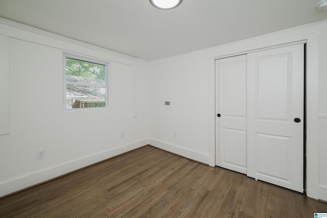 unfurnished bedroom featuring a closet and dark wood-type flooring