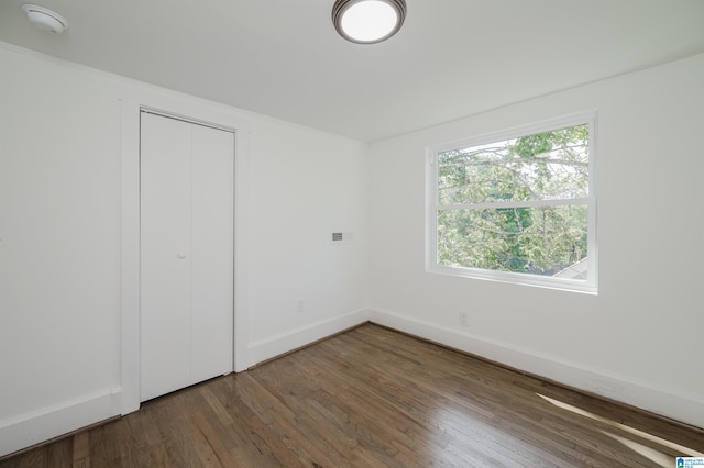 unfurnished bedroom featuring a closet and dark wood-type flooring