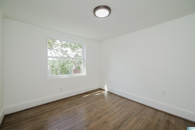 spare room featuring baseboards and wood finished floors