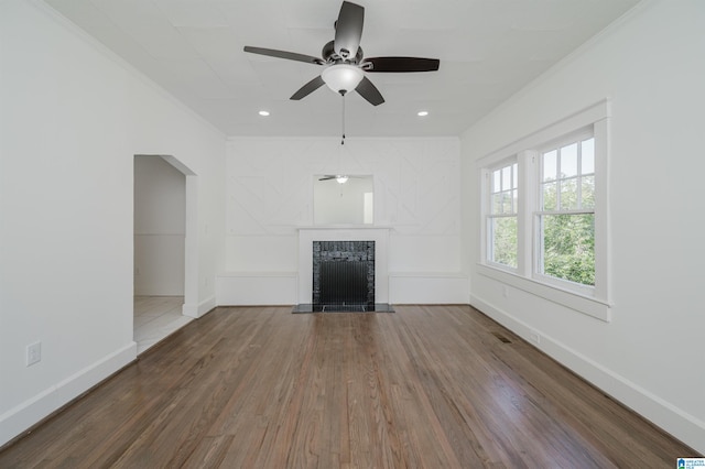 unfurnished living room featuring crown molding, ceiling fan, a brick fireplace, and hardwood / wood-style flooring