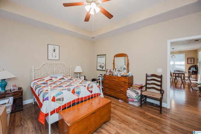 bedroom featuring ceiling fan, hardwood / wood-style floors, and a raised ceiling