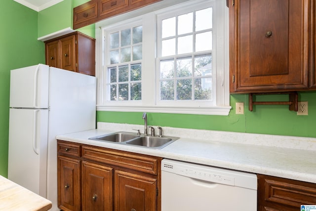 kitchen with white appliances, crown molding, and sink