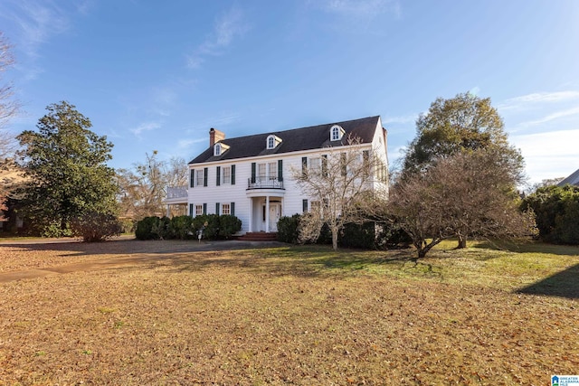 colonial house with a balcony and a front lawn