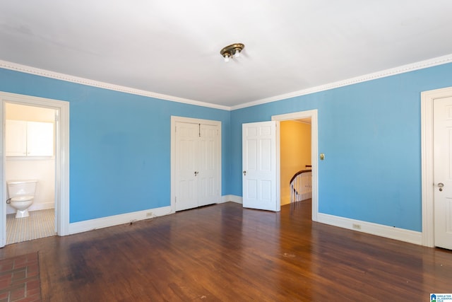 unfurnished bedroom featuring ensuite bathroom, dark wood-type flooring, and crown molding