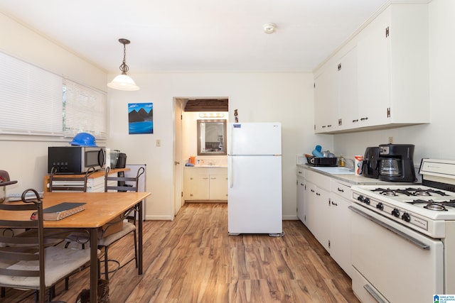 kitchen featuring white cabinetry, white appliances, crown molding, decorative light fixtures, and hardwood / wood-style floors