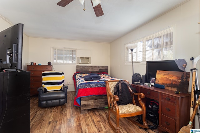 bedroom featuring ceiling fan, crown molding, hardwood / wood-style floors, and multiple windows