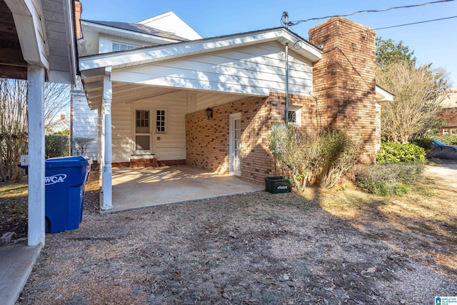 305 S St E, Talladega, AL 35160 - exterior space with an attached carport, brick siding, and a chimney