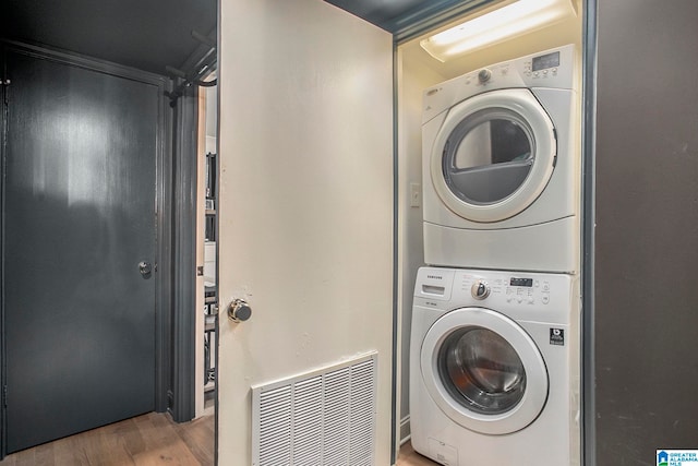 washroom with stacked washer / dryer and wood-type flooring