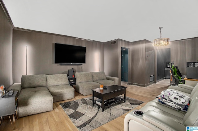 living room featuring crown molding, a chandelier, and light wood-type flooring