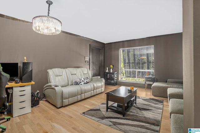 living room featuring a notable chandelier, ornamental molding, and light wood-type flooring