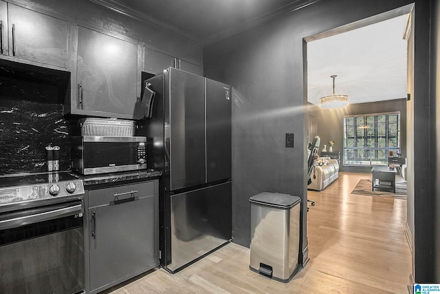 kitchen featuring crown molding, appliances with stainless steel finishes, light hardwood / wood-style flooring, and a chandelier