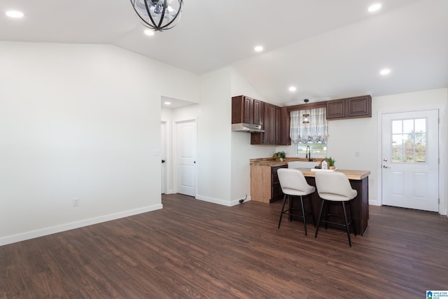 kitchen featuring sink, a breakfast bar area, vaulted ceiling, and dark hardwood / wood-style floors