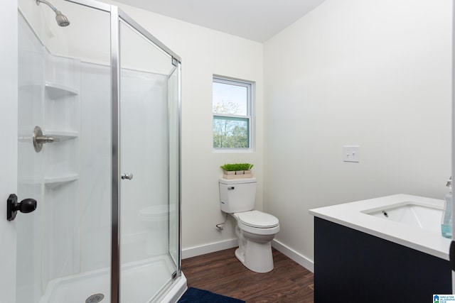 bathroom with toilet, a shower with shower door, vanity, and wood-type flooring