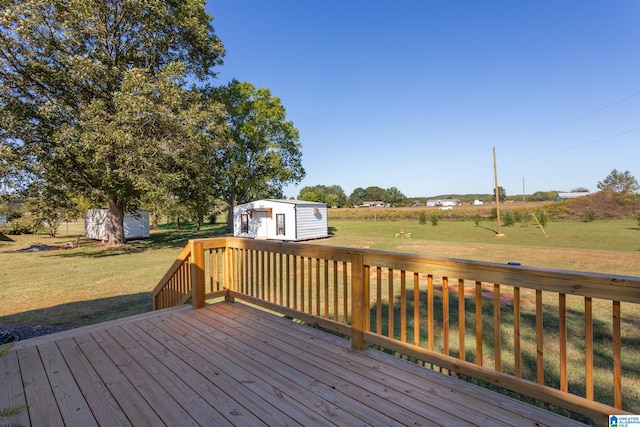 deck with a rural view, a storage unit, and a lawn