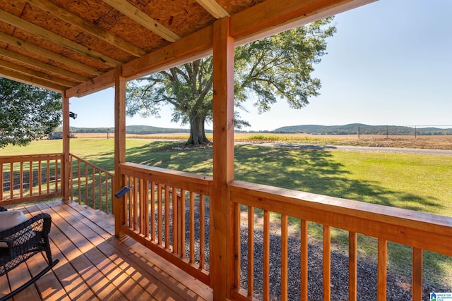 deck featuring a rural view, a mountain view, and a lawn