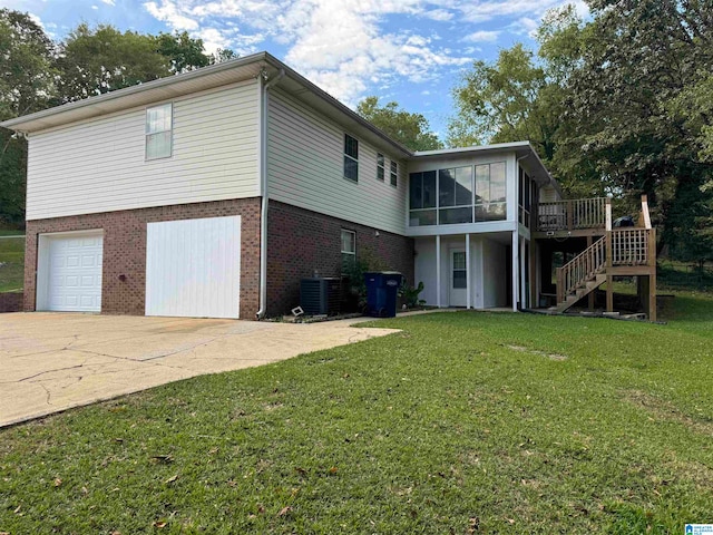 back of house with cooling unit, a garage, a sunroom, a wooden deck, and a lawn