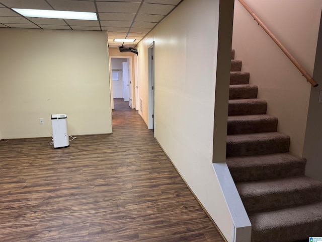 hallway featuring a drop ceiling and dark hardwood / wood-style flooring