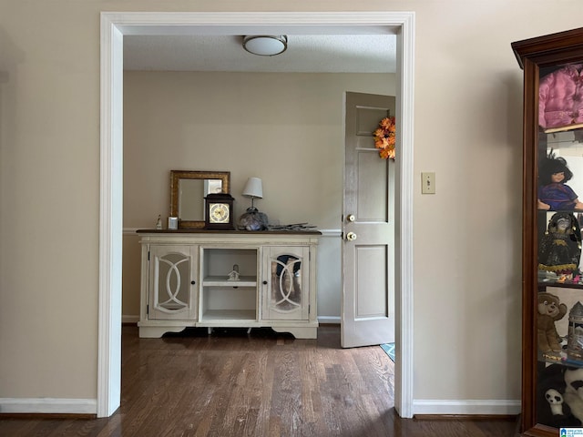 hallway with a textured ceiling and dark hardwood / wood-style floors