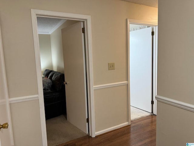 corridor with ornamental molding, a textured ceiling, and dark hardwood / wood-style floors