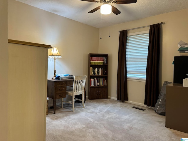 carpeted home office featuring a textured ceiling and ceiling fan