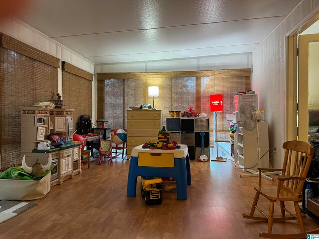 rec room featuring brick wall and hardwood / wood-style floors