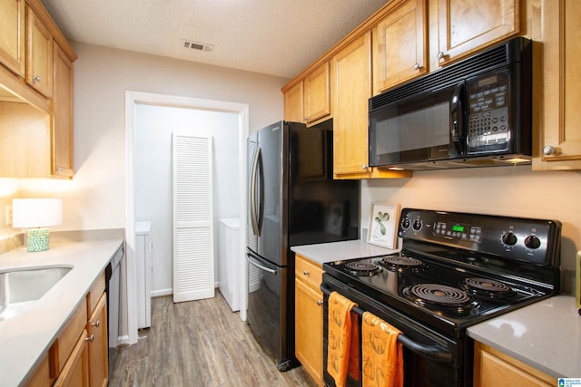 kitchen with a textured ceiling, light hardwood / wood-style flooring, sink, and black appliances