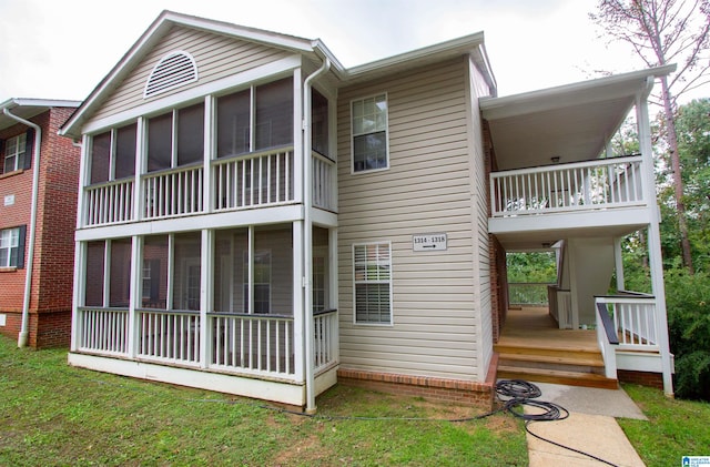 rear view of property featuring a sunroom, a balcony, and a yard