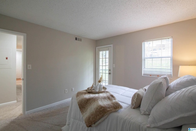 bedroom featuring light colored carpet and a textured ceiling