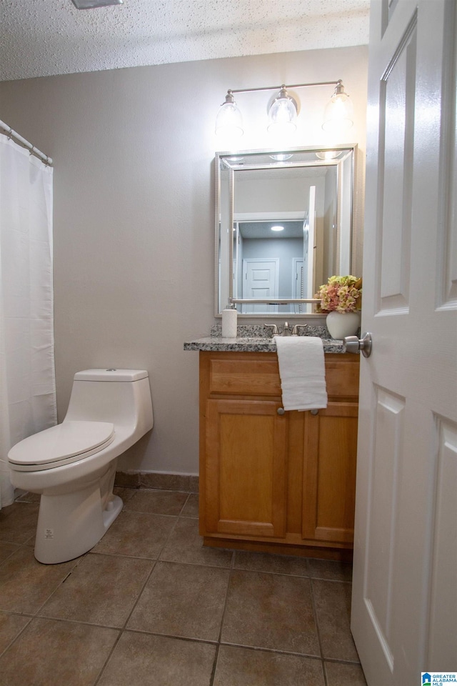 bathroom with tile patterned floors, a textured ceiling, vanity, and toilet