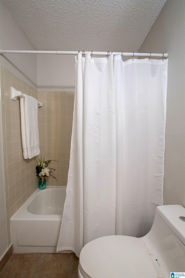 bathroom with a textured ceiling, shower / tub combo, tile patterned flooring, and toilet