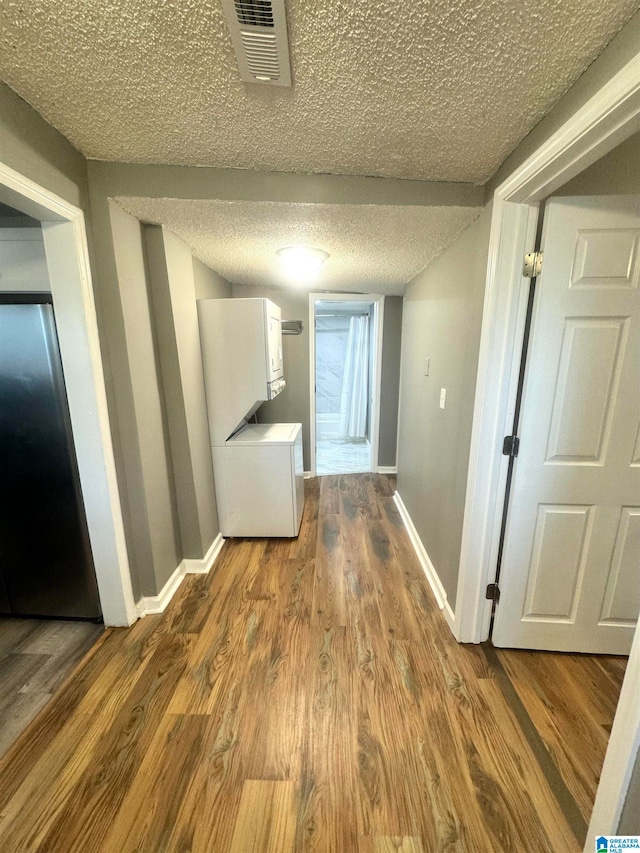 hallway with washer / clothes dryer, a textured ceiling, and hardwood / wood-style floors