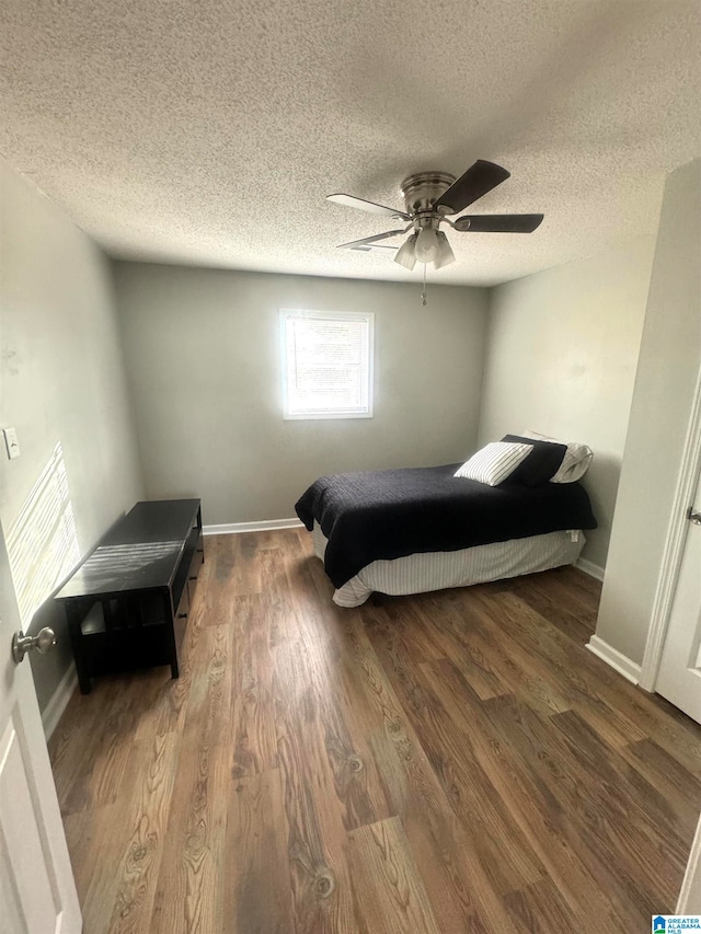 bedroom with a textured ceiling, ceiling fan, and dark hardwood / wood-style flooring