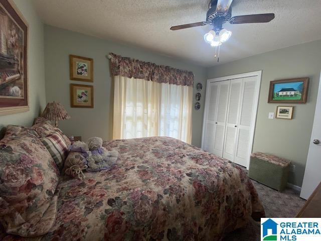 carpeted bedroom featuring a closet, ceiling fan, baseboards, and a textured ceiling