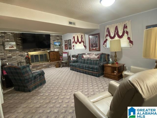living area featuring a brick fireplace, visible vents, and carpet floors