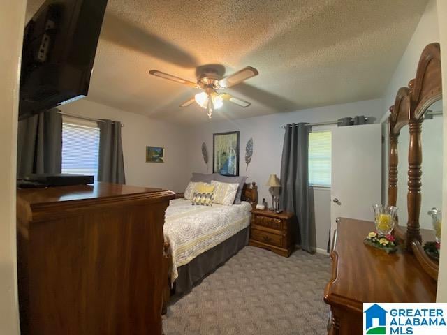 carpeted bedroom featuring ceiling fan and a textured ceiling