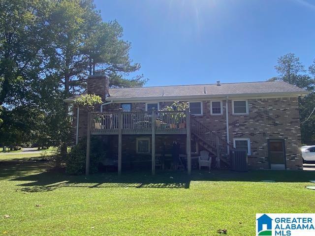 back of property with a yard, a chimney, stairs, brick siding, and a wooden deck