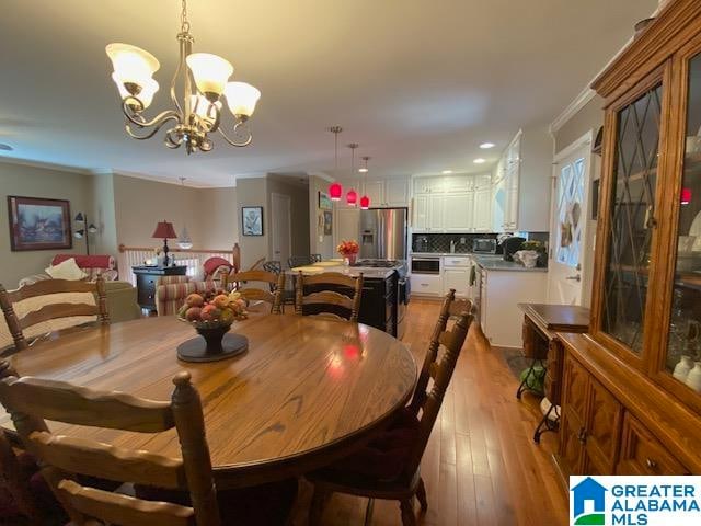 dining room with a notable chandelier, crown molding, and light hardwood / wood-style floors