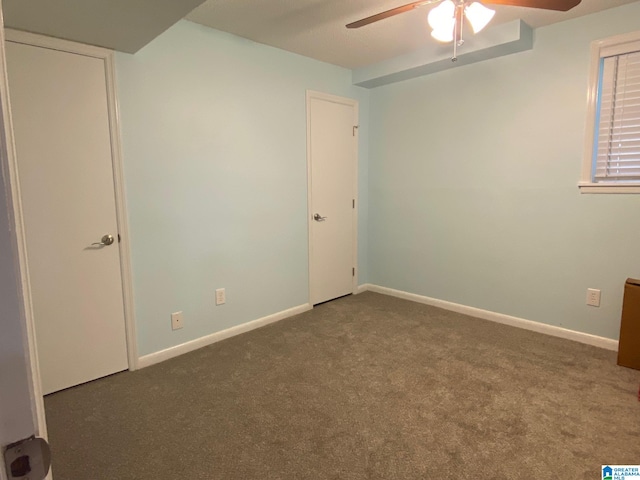 unfurnished bedroom with dark carpet and ceiling fan