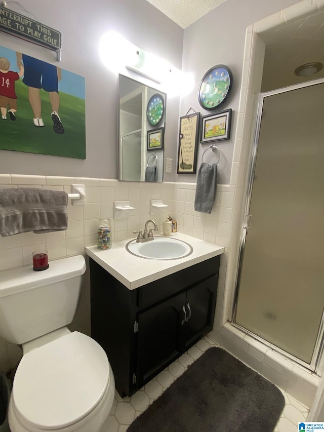 bathroom with tile patterned flooring, toilet, tile walls, a shower with door, and vanity