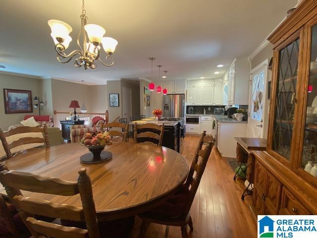 dining area with a chandelier, light wood-style flooring, and crown molding