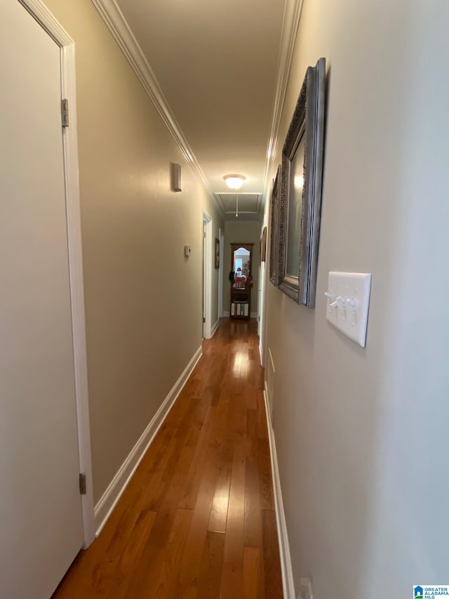 hallway with hardwood / wood-style floors, attic access, baseboards, and ornamental molding