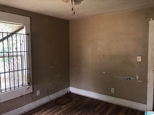 spare room featuring a textured ceiling, dark hardwood / wood-style floors, and a healthy amount of sunlight