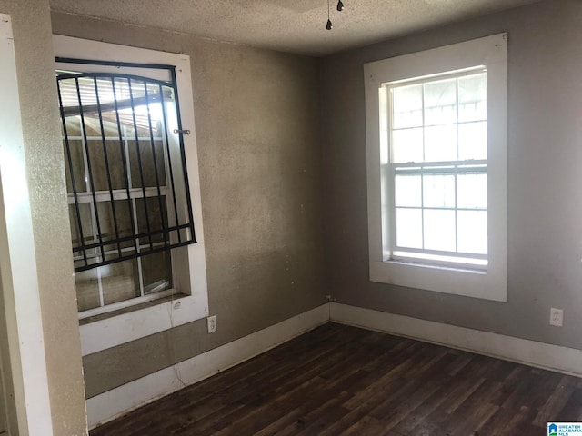 empty room featuring a textured ceiling and dark hardwood / wood-style flooring