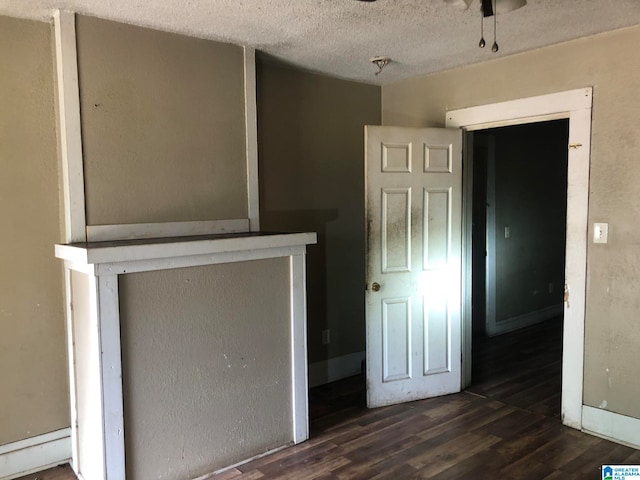 unfurnished living room featuring a textured ceiling and dark wood-type flooring