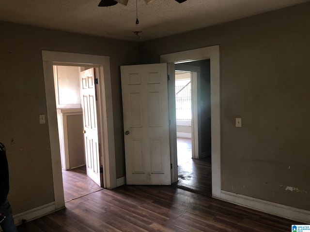 unfurnished bedroom with ceiling fan, a textured ceiling, and dark hardwood / wood-style flooring