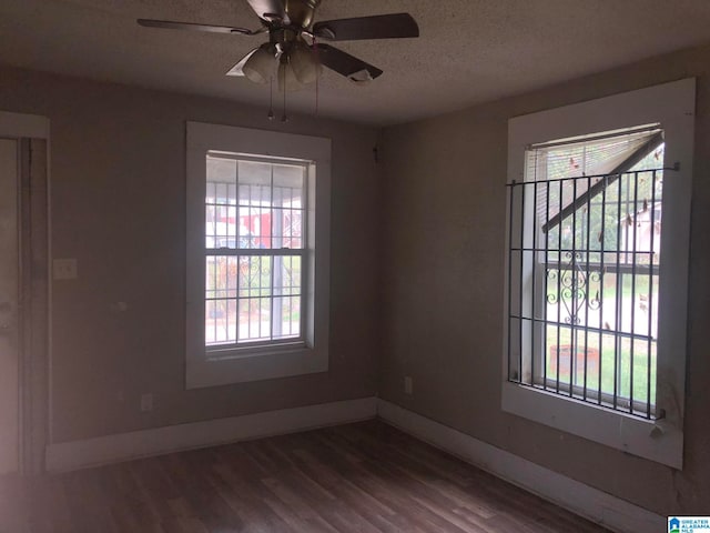 unfurnished room featuring a textured ceiling, dark hardwood / wood-style floors, and a healthy amount of sunlight