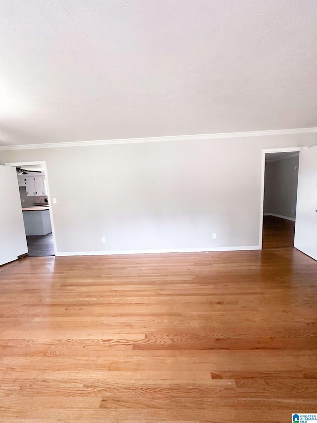 unfurnished room with light wood-type flooring and crown molding