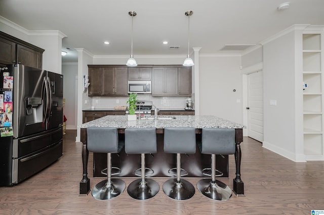 kitchen with pendant lighting, dark hardwood / wood-style floors, an island with sink, backsplash, and appliances with stainless steel finishes